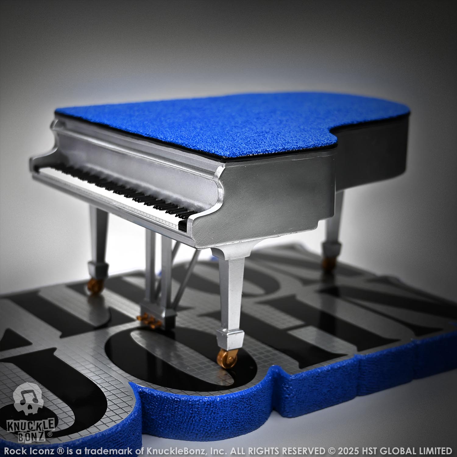 Blue and silver grand piano on a reflective surface with 'Elton John' on the statue base