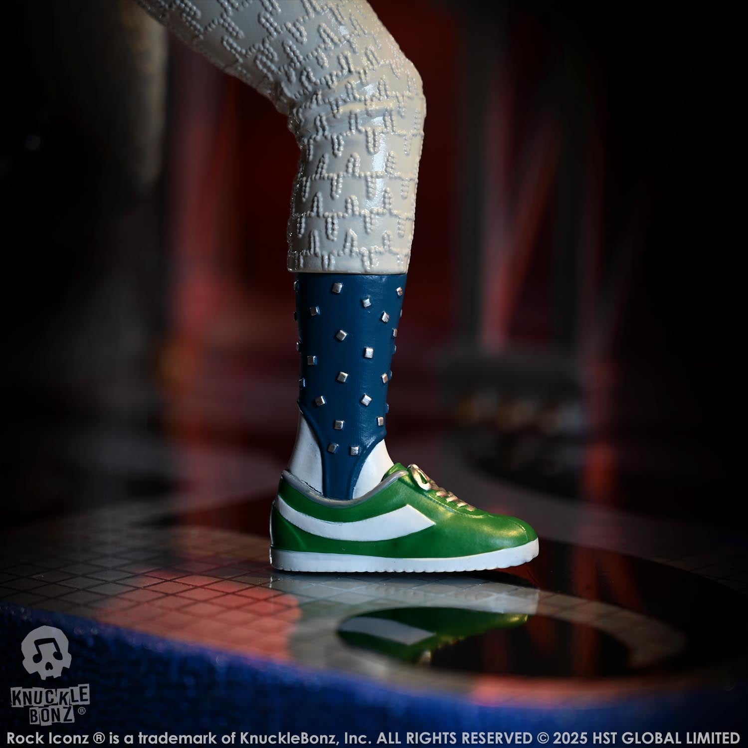Green and white sneaker with blue sock worn by a figure on a reflective surface.