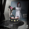 Limited edition statue of a figure in a silver bodysuit with feathers and red hair, standing with one foot on a raised platform. The statue is of Marilyn Manson and is part of the Rock Iconz KnuckleBonz collection.