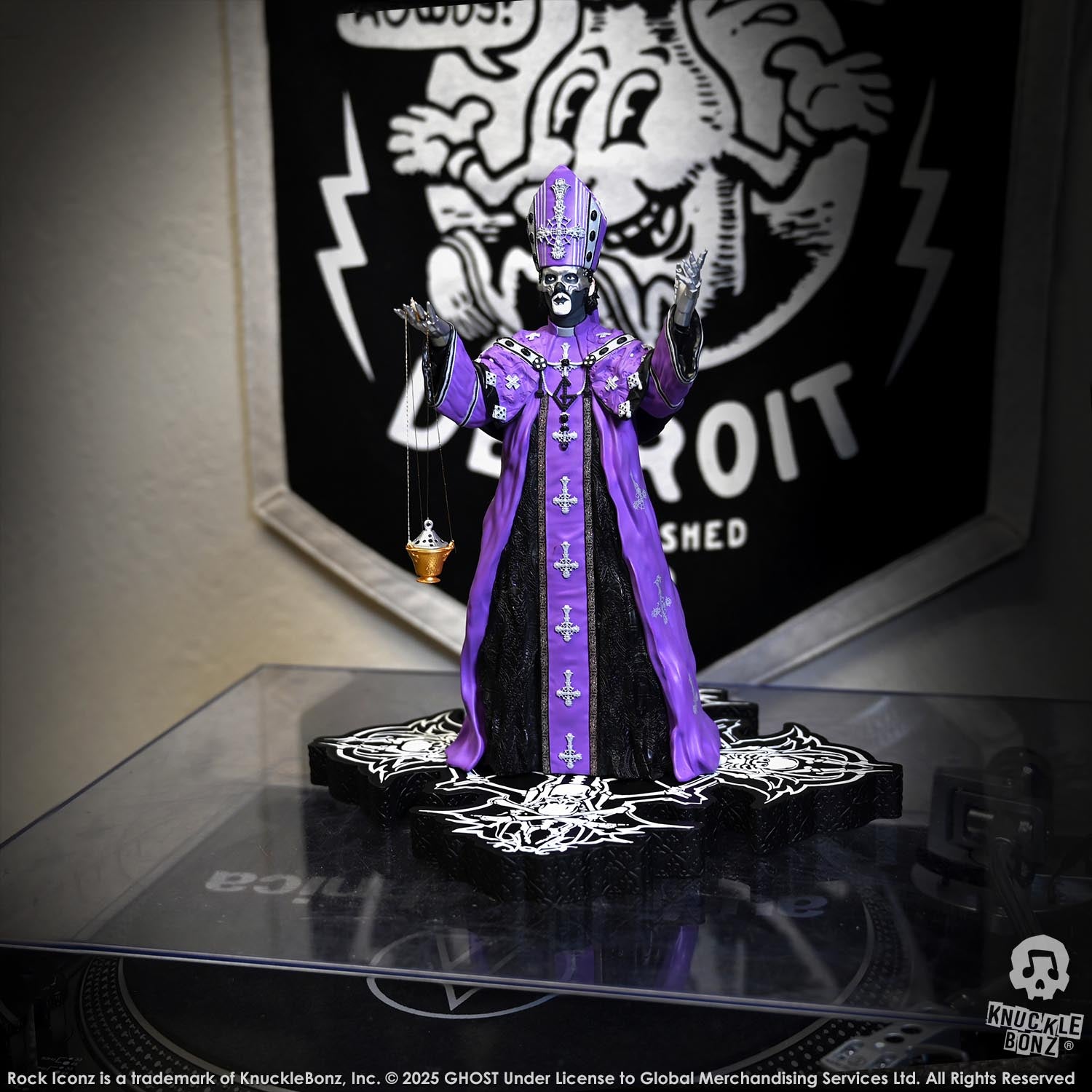 Statue of Papa V Perpetua from Ghost in a purple robe with a black background featuring a logo.